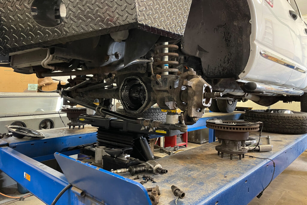 A pickup truck on a hydraulic lift with its rear axle exposed in a repair shop.