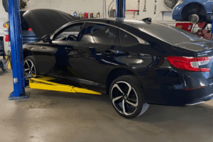 Fall car maintenance, auto repair in Belton, MO by Belton Transmission & Complete Auto Repair. Image of a black Honda Accord on a hydraulic lift, showcasing professional transmission service to ensure reliability and safe vehicle performance.