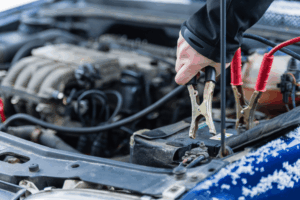 Car electrical system service, auto repair in Belton, MO by Belton Transmission & Complete Auto Repair. Image of a technician attaching jumper cables to a vehicle battery in cold weather. Highlighting the shop’s commitment to reliable starting power and safe winter performance.