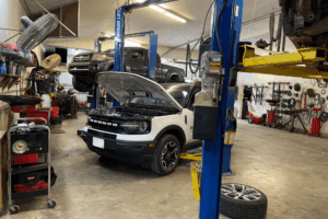 Car maintenance, auto repair in Belton, MO by Belton Transmission & Complete Auto Repair. Image of a Ford Bronco inside a professional auto repair shop with the hood open on a lift, highlighting thorough vehicle inspection and routine maintenance for reliable performance and safety.