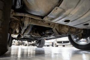 Drivetrain repair in Belton, MO by Belton Transmission & Complete Auto Repair. Image of a vehicle’s undercarriage showing driveshaft, differential, and suspension components on a shop floor. Highlighting smooth power transfer, drivetrain reliability, and safe vehicle performance.