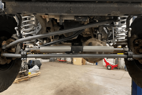 Suspension and chassis repair in Belton, MO by Belton Transmission & Complete Auto Repair. Image of a vehicle’s rear suspension with coil springs, control arms, and steering stabilizer on a lift. Highlighting improved handling, drivetrain stability, and safe, smooth ride performance.